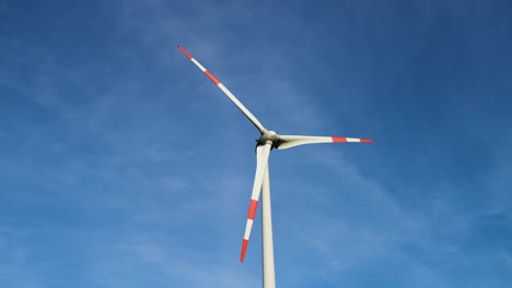 toma de ángulo bajo de turbinas eólicas trabajando y generando energía eléctrica verde en una granja eólica bajo un cielo azul en un día soleado