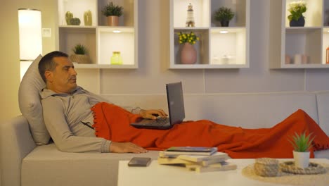 tired and exhausted man using laptop lying down.