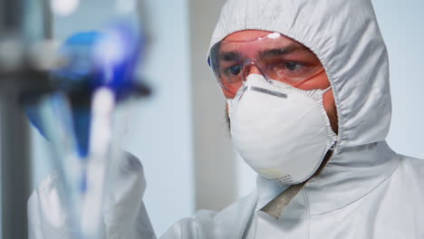 close up of chemist holding blood sample wearing coverall