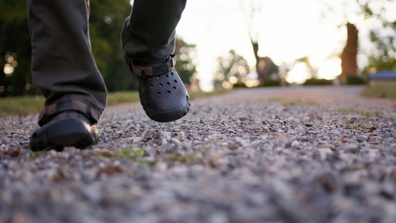 toma a nivel del suelo de un hombre caminando sobre un camino de grava