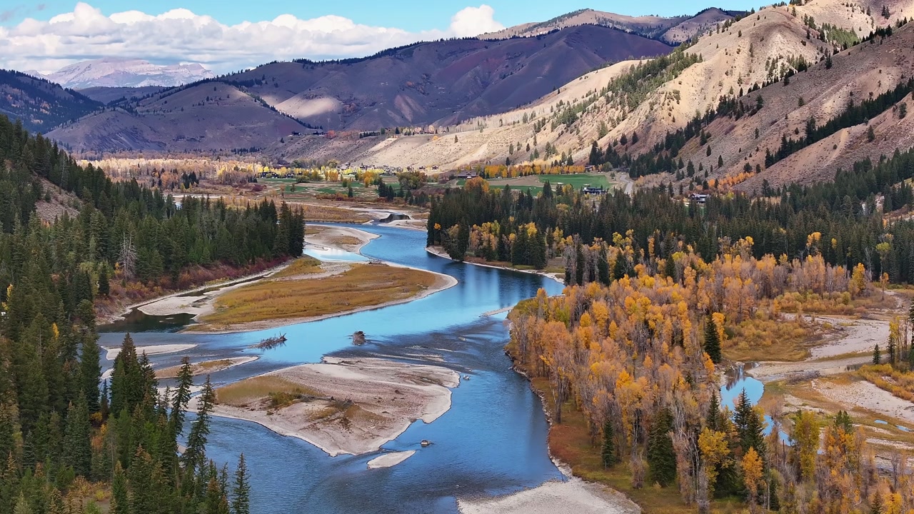 Winding river with sandbars and forest along mountain valley in Wyoming, serene natural rural beauty