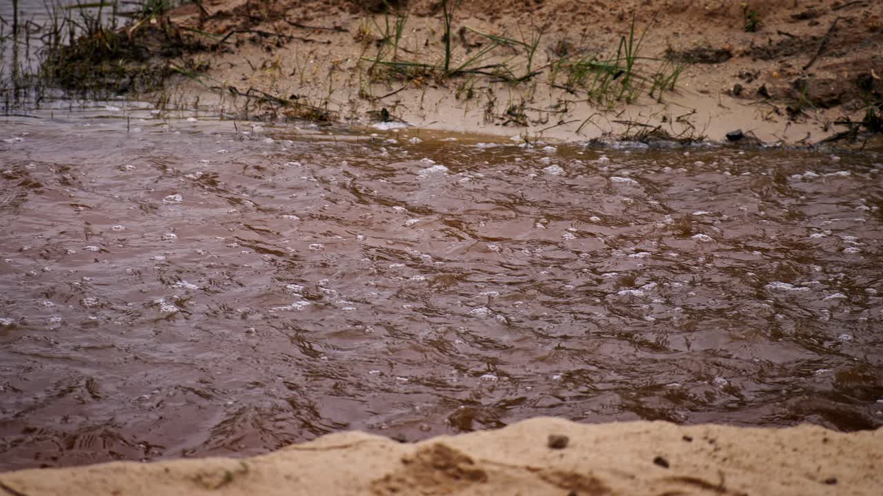 Super slow motion di acqua sporca marrone che scorre con bolle in un ruscello di fiume