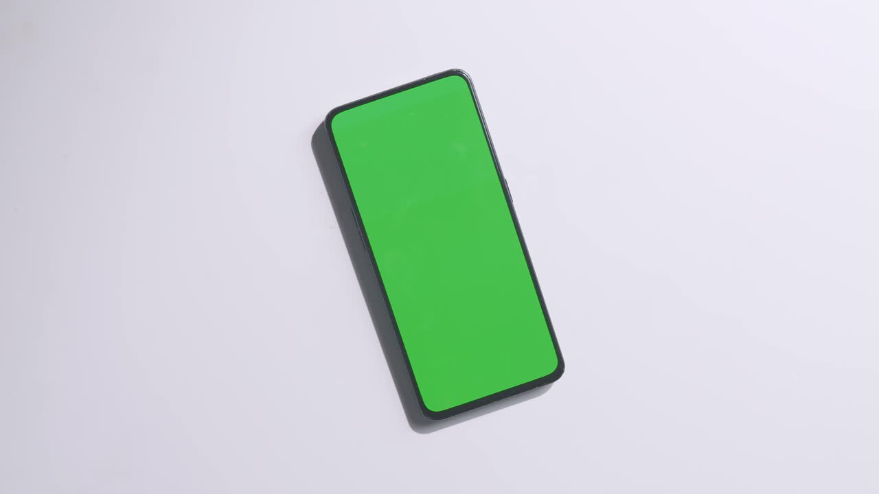 vista de arriba hacia abajo de una computadora portátil con pantalla verde simulada pantalla chromakey en un escritorio de oficina de madera al lado de la libreta con bolígrafos, gafas y un vaso de agua.
