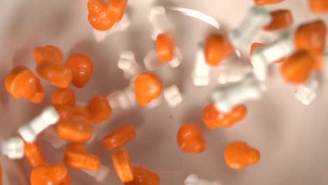 Close-up-of-orange-skulls-and-bones-shaped-candy-falling-on-a-plate