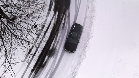 Toma-De-Pájaro-De-Un-Coche-Negro-En-Una-Rotonda-En-Invierno.