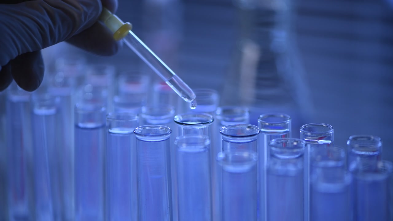 Primo piano di liquido che viene fatto cadere in una provetta in laboratorio