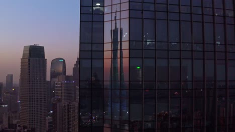 Guangzhou-Canton-Tower,-Der-Sich-Bei-Sonnenuntergang-In-Den-Glasscheiben-Des-Bürogebäudes-In-Der-Innenstadt-Von-Cbd-Widerspiegelt