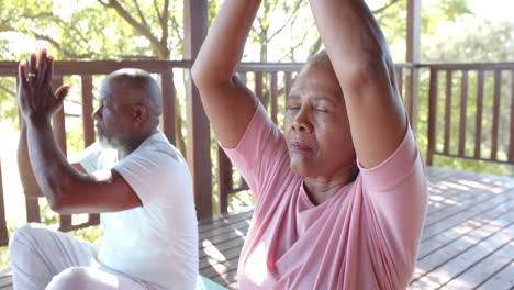 Focused-senior-african-american-couple-practicing-yoga-meditation-on-sunny-terrace,-slow-motion