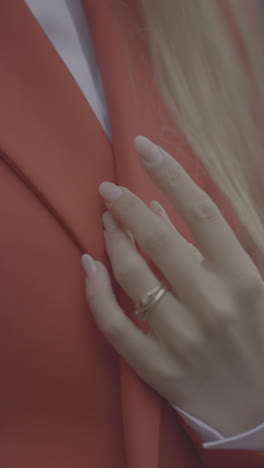 woman's hand with ring on orange jacket
