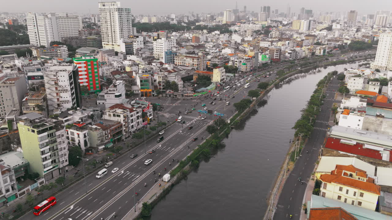 Vietnam'ın Ho Chi Minh şehrinde, bir nehir kenarındaki büyük bir şehir otoyolundaki trafiğin drone görüntüsü. Hareketli bir Asya metropolünde yoğun kentsel binaları ve altyapıyı sergiliyor.