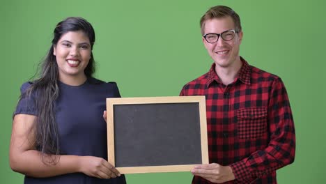 young multi-ethnic business couple together against green background