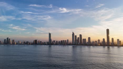 drone captures gold coast skyline transitioning from day to night, highlighting vibrant skies and reflective ocean waters