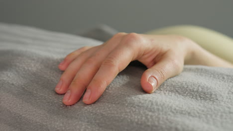 close up of elegant woman hands resting on body under blanket during spa appointment with soft lighting, capturing calm and poised moment in serene wellness environment, enhanced by ambient decor