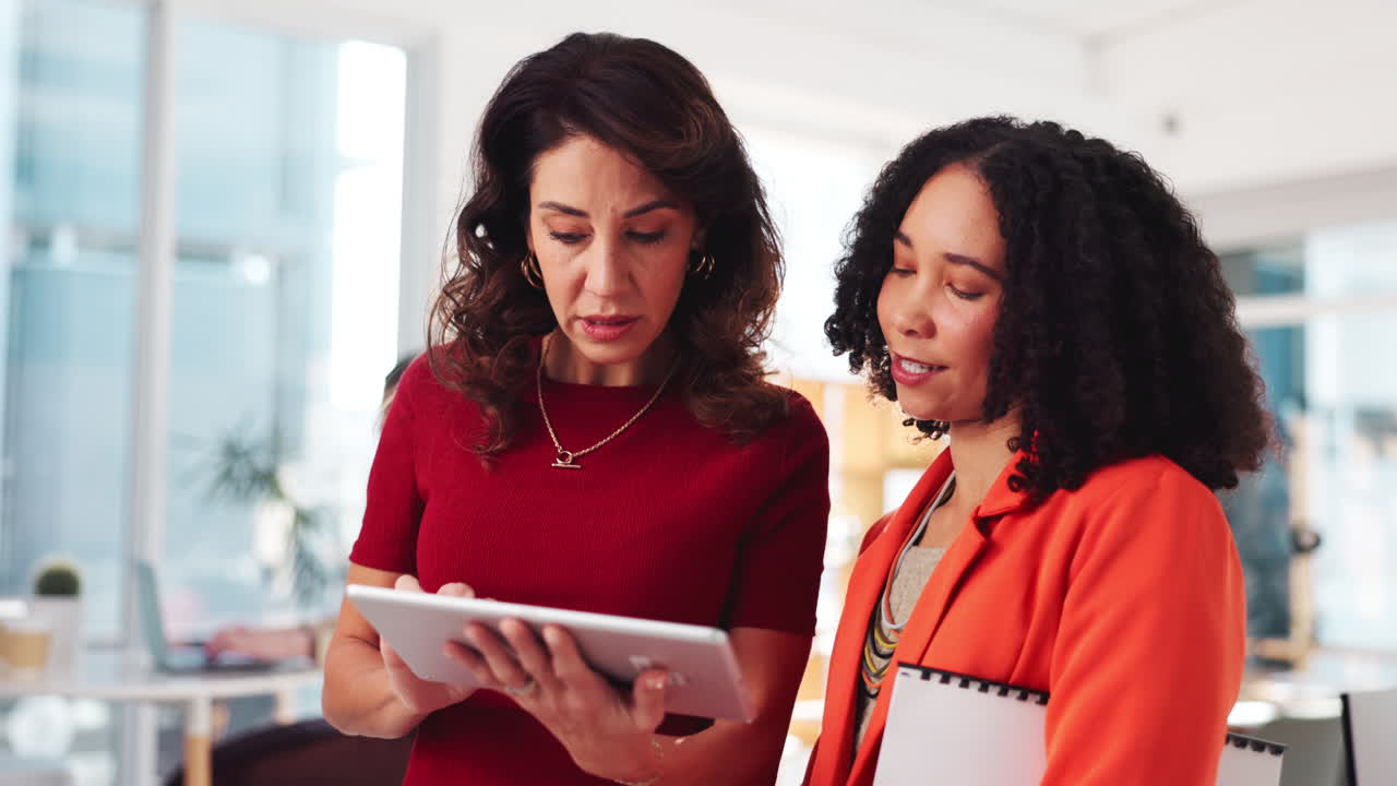 dos mujeres de negocios colaborando en una tableta en una oficina moderna