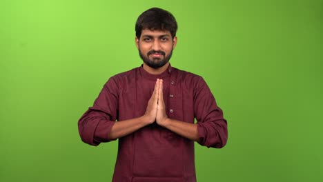 young attractive man showing namaste gesture, isolated on green screen