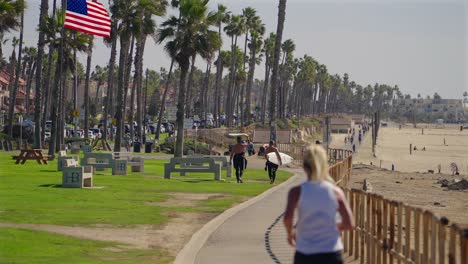 Mujer-Rubia-Con-Cola-De-Caballo-Trotando-En-El-Carril-Bici-En-Huntington-Beach,-California