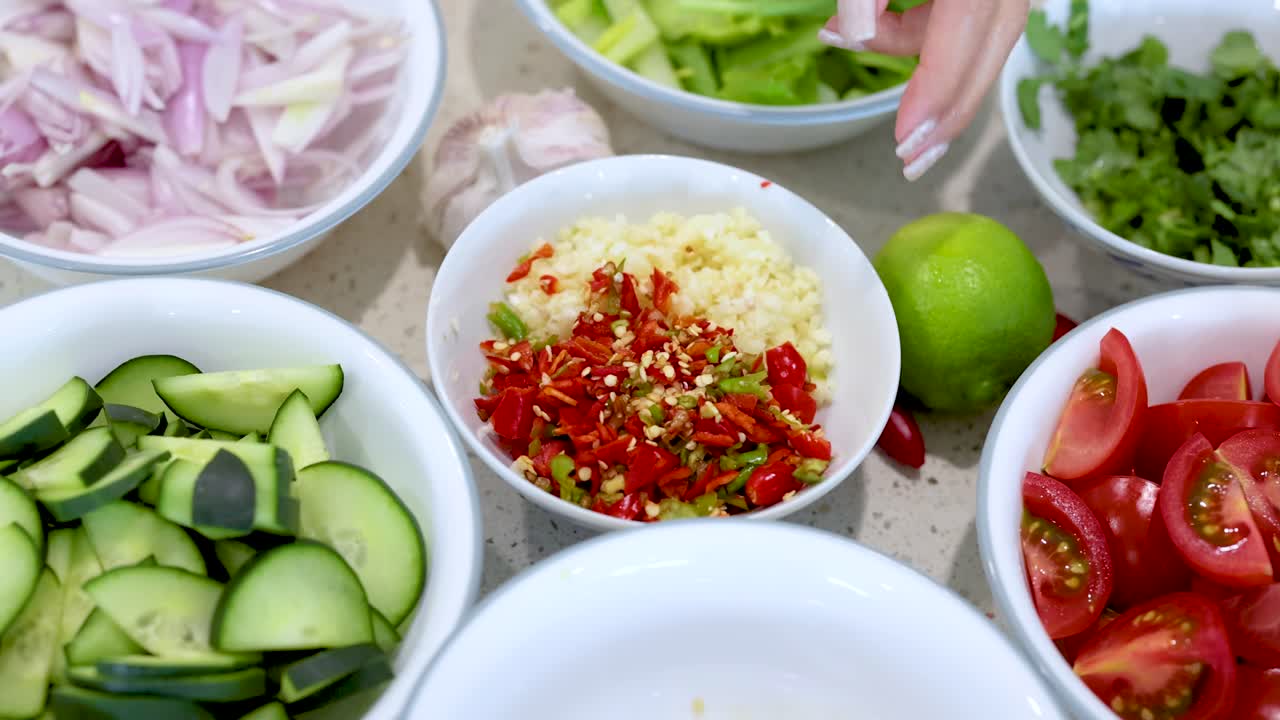 Hands arranging fresh vegetables and spices on a kitchen counter under bright lighting, creating a colorful and inviting scene