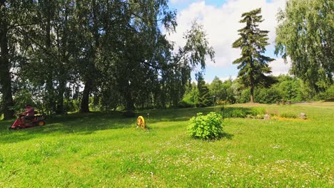 static time lapse person sit on red lawn mower and cut grass on backyard in lithuania countryside