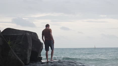 tipo caminando en la costa rocosa de la playa para admirar el océano ondulado