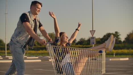 gente alegre una pareja un hombre y una mujer al atardecer viajan en carros de supermercado en cámara lenta.