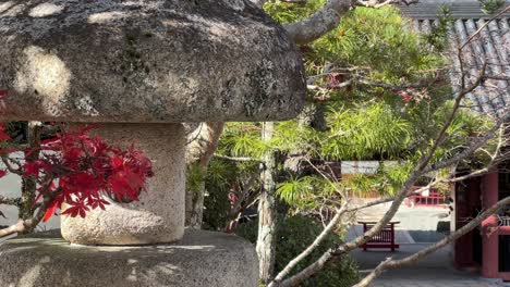 stunning stone pillar with red maple leaves at japanese buddhist temple