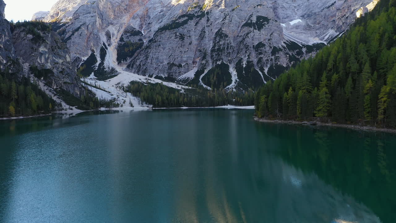 Cinematic drone shot starting on the emerald colored water then tilting up to the beautiful Lago Di Braies, Italian Dolomites, in South Tyrol Italy