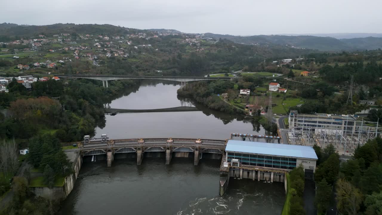 High angle aerial overview of power plant and dam with bridge reflection in water
