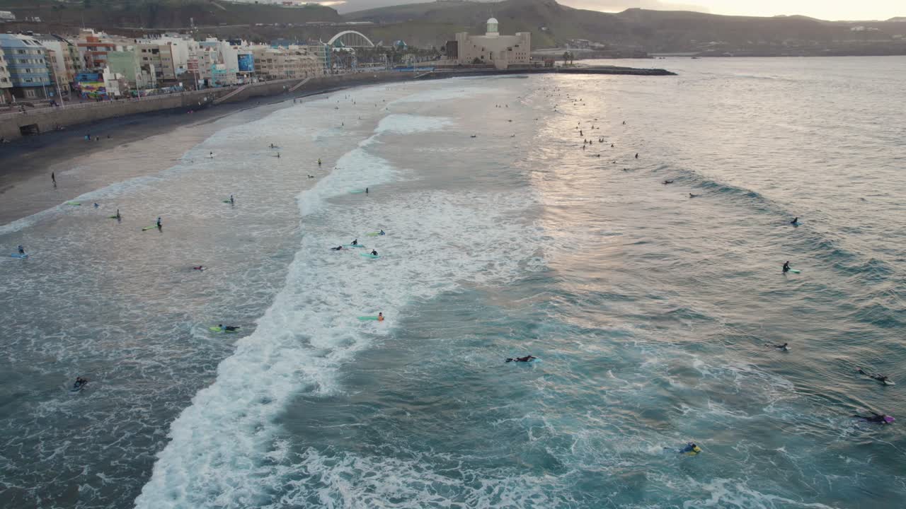 Surfisti che cavalcano le onde alla spiaggia di Las Canteras, Isole Canarie, Europa, ripresa aerea al rallentatore