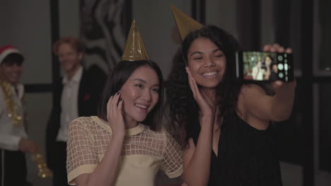 amigas felices multiétnicas tomándose un selfie en la fiesta de fin de año