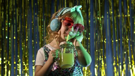 futuristic hipster teen girl with pineapple fruit juice listening to music in headphones, dancing