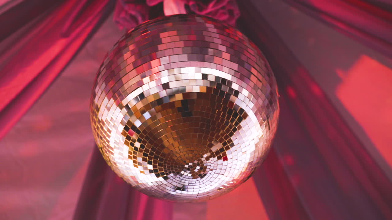 Disco Ball spins at the beautiful wedding. Pink drapes are tented over the glittering globe.