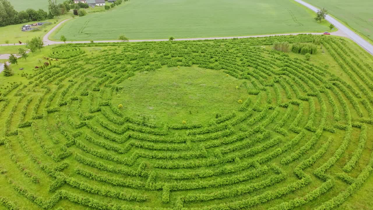Circular green maze in cloudy daylight reflecting unclear paths and struggles
