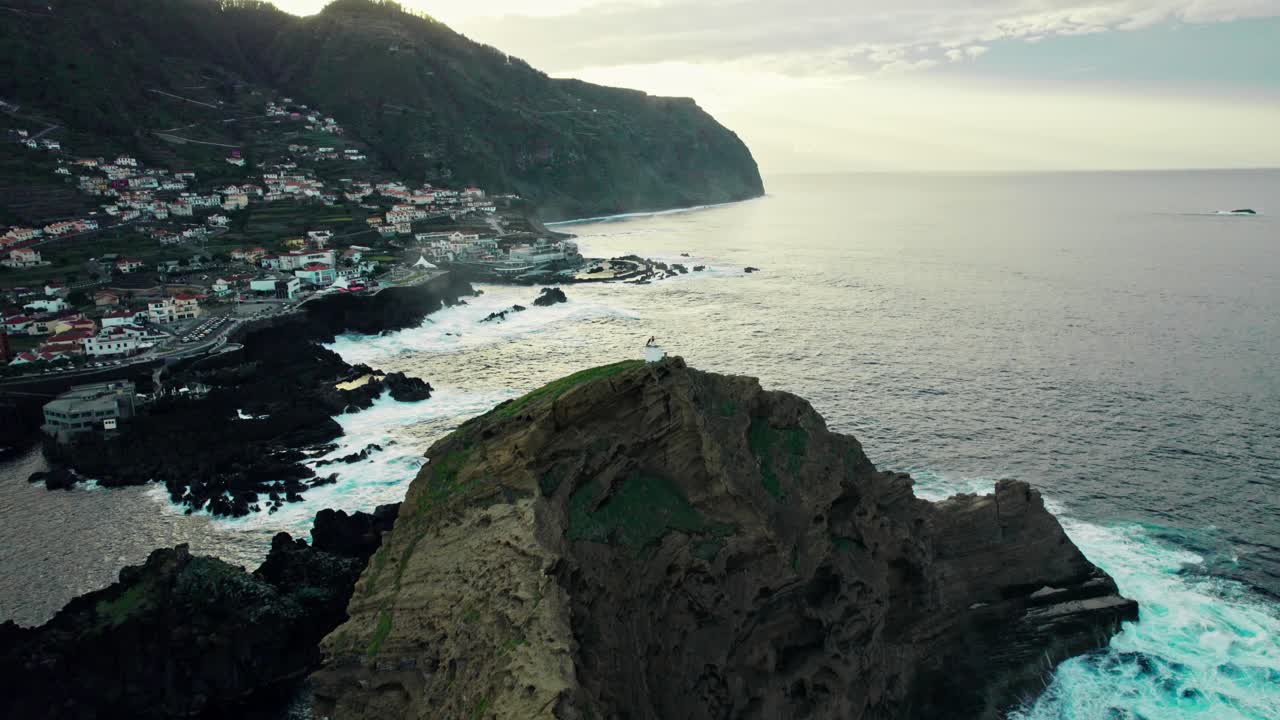 Vista aerea di una città costiera con uno sperone roccioso e onde oceaniche
