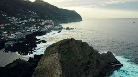 aerial view of a coastal town with a rocky outcrop and ocean waves