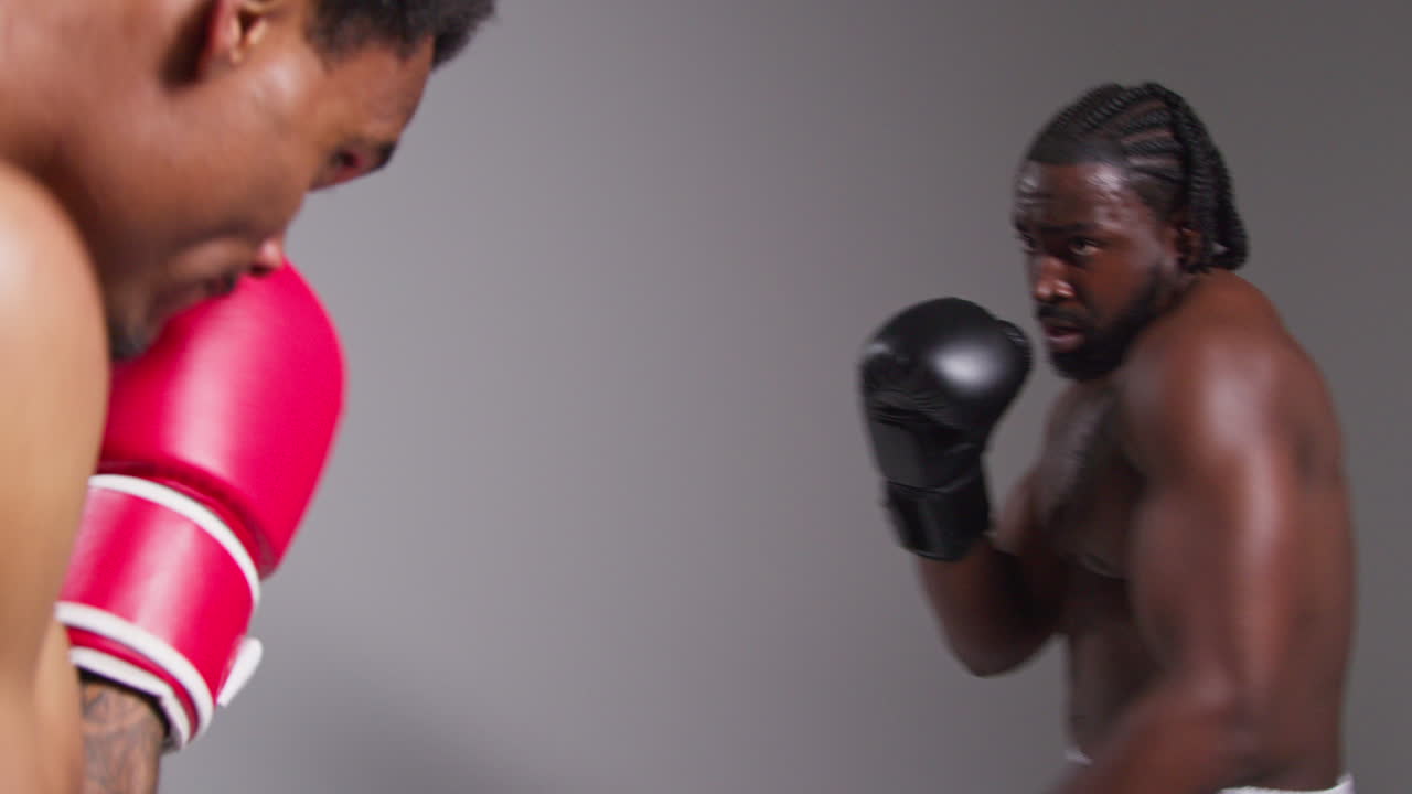 Real Time Action Studio Shot Of Two Male Boxers Wearing Gloves Fighting In Boxing Match Against Grey Background 6