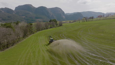 tractor on scenic farm spraying organic fertilizer on pasture