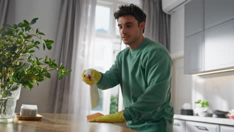 cleaning worker removing dust kitchen closeup. positive man spraying detergent