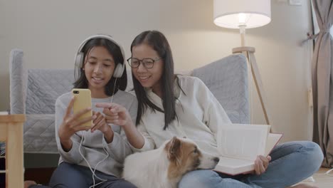 happy family of asian mother and daughter using mobile phone together at night.