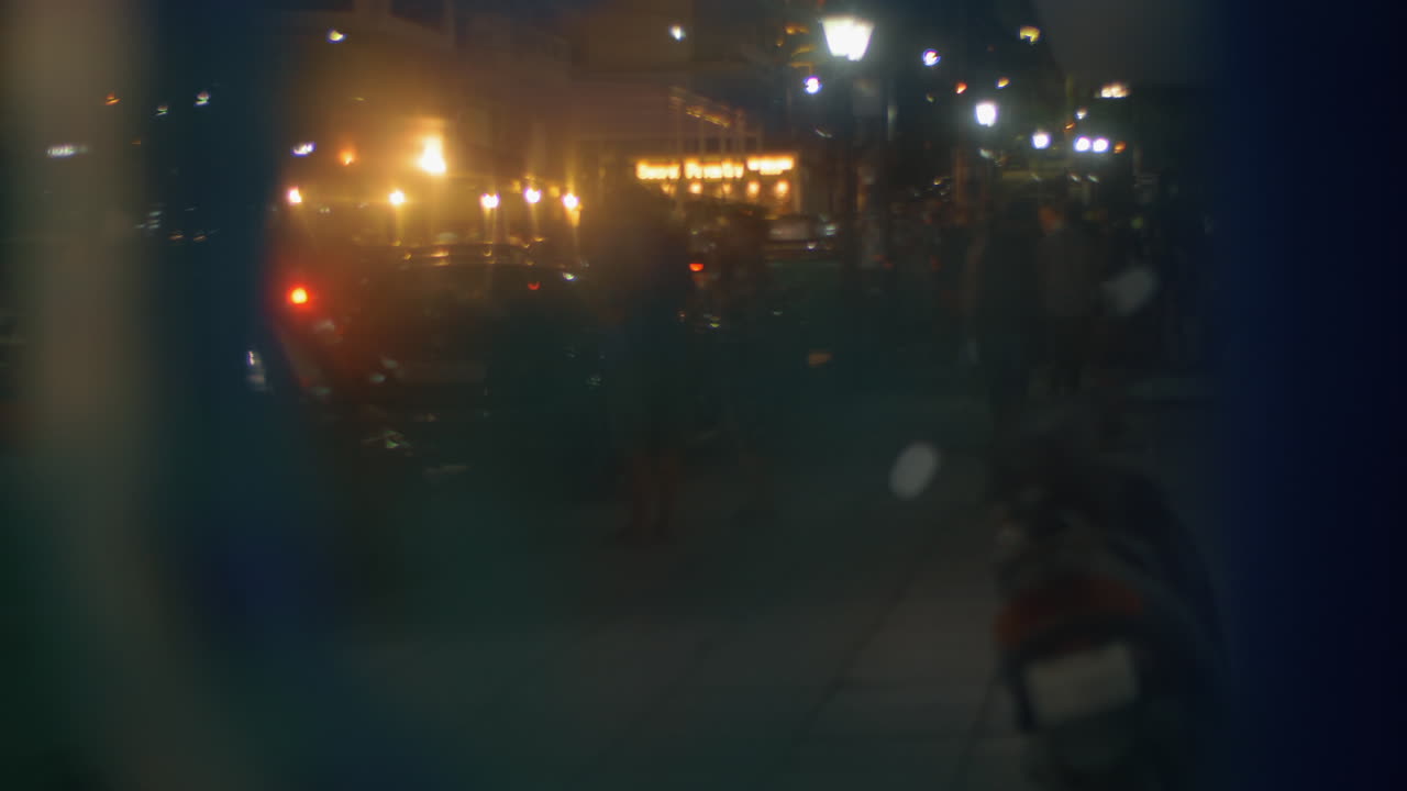 calle de la ciudad de la noche con la gente y los coches vista a través del vidrio
