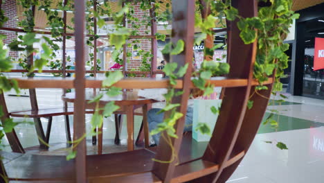 dama sentada en asientos vip en un restaurante de clase, centrada en su teléfono con gente a su alrededor, luces digitales parpadean en el fondo, creando una atmósfera vibrante en un restaurante a la moda