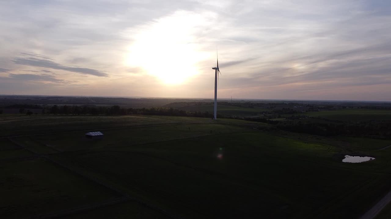 일몰 동안 농지 필드 위에 풍력 터빈 실루엣의 공중
