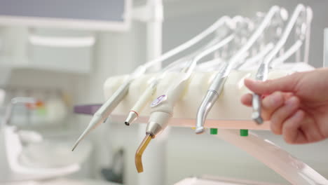 close-up view of hygienic metal dental tool set as one is picked up by hand