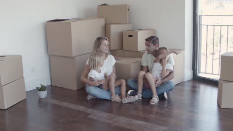 parents and two girls sitting on floor near boxes