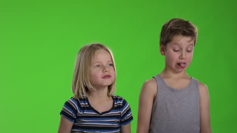 dos niños haciendo caras frente a la pantalla verde