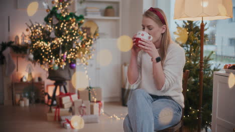 attractive woman drinking coffee on chair at home during christmas