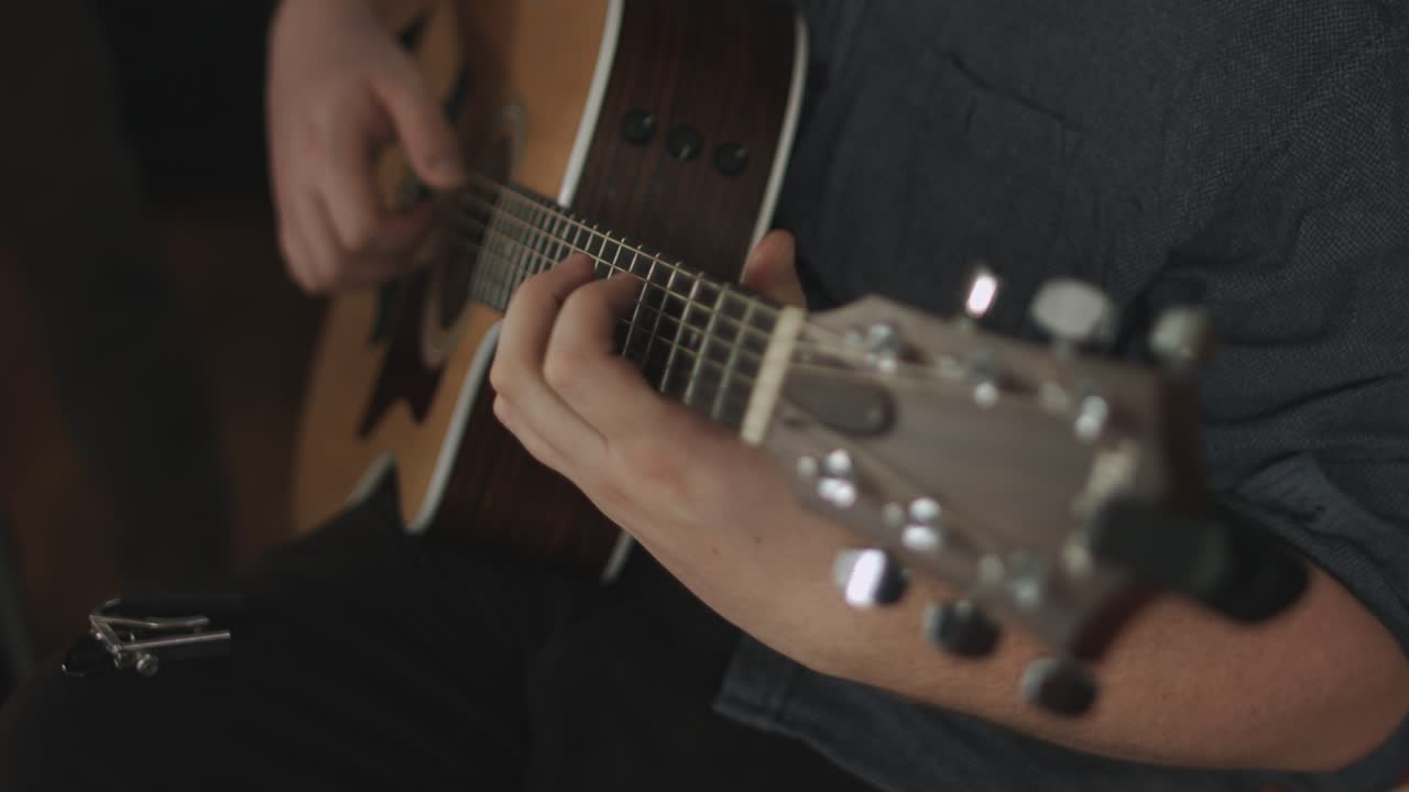 Close up of a western acoustic guitars body being played by a professional musician during a recording session. Shot in 4K. Smooth panning