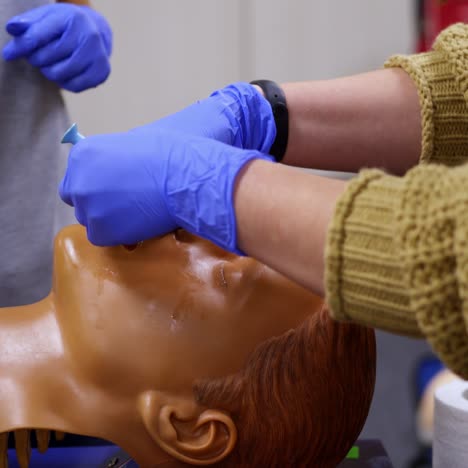 training course in medical center. medical instructing student to perform treatment procedure on a dummy head. close-up