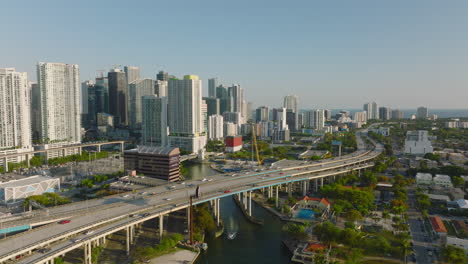 Aerial-panoramic-footage-of-modern-urban-borough-with-tall-apartment-towers.-Forwards-fly-over-busy-multilane-highway.-Miami,-USA