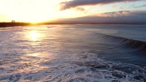 static aerial shot of big waves during sunrise at rusty pipes surf spot on maui hawaii