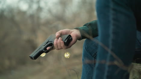 una vista cercana de un hombre mirando intensamente hacia el lado, sosteniendo una pistola, el fondo presenta un bosque, con tres bolas borrosas como luz amarilla vista
